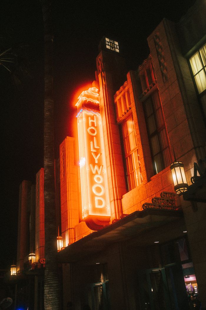 Low-angle shot of an illuminated Hollywood sign on a building at night with vibrant neon lights.